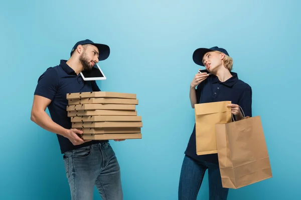 Mensajeros Interraciales Que Aceptan Pedidos Mientras Sostienen Paquetes Azul — Foto de Stock