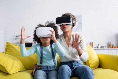 Heyecanlı Afrikalı Amerikalı anne ve kızı evde kulaklık takıyor.