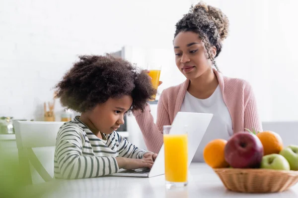 Smiling African American Woman Looking Concentrated Daughter Using Laptop Blurred — Stock Photo, Image