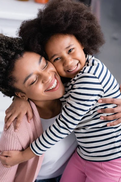 joyful african american mom and daughter embracing at home