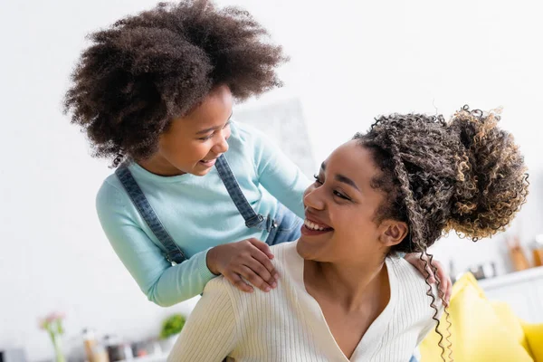 happy african american child touching shoulders of happy mother at home