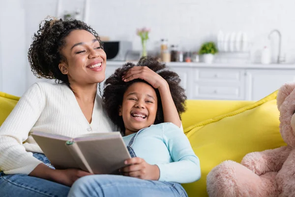 Cheerful African American Woman Touching Head Laughing Daughter While Sitting — Stock Photo, Image