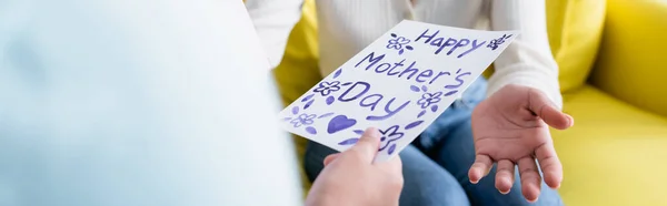 cropped view of child with happy mothers day card near african american mom, banner