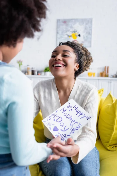 excited african american woman near daughter with happy mothers day card on blurred foreground