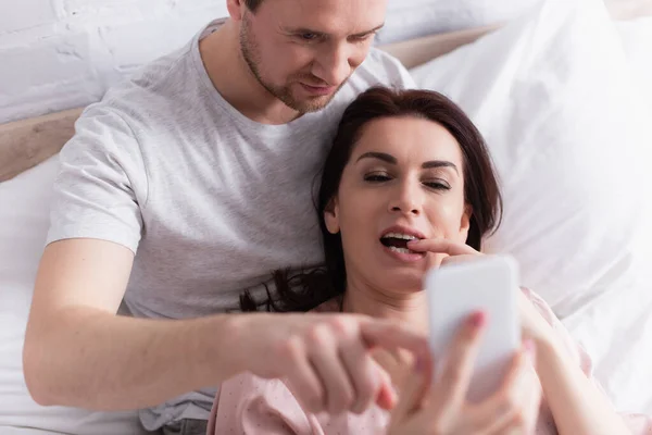 Woman Using Smartphone Blurred Foreground Husband Bedroom — Stock Photo, Image