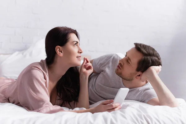 Brunette Woman Holding Smartphone Husband Bed — Stock Photo, Image