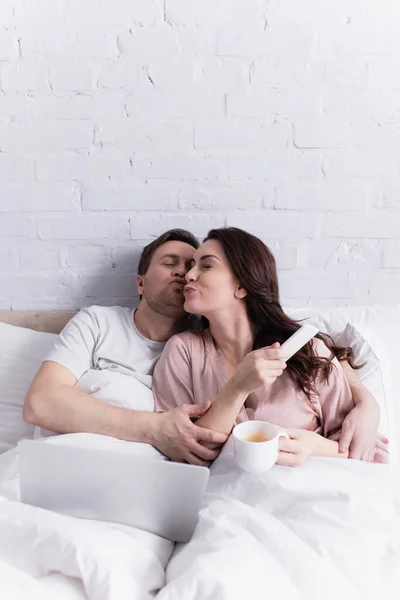 Woman Coffee Smartphone Kissing Husband Laptop Bed — Stock Photo, Image