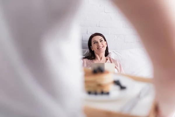 Mulher Sorridente Com Livro Olhando Para Marido Com Panquecas Primeiro — Fotografia de Stock