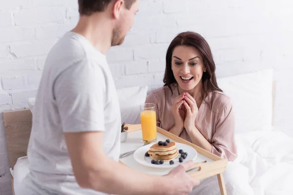 Happy Woman Looking Tasty Pancakes Orange Juice Tray Husband Bedroom — Stock Photo, Image