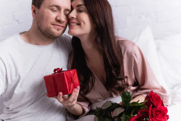 Mulher Sorridente Segurando Presente Rosas Perto Marido Quarto — Fotografia de Stock