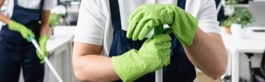 Ofiste paspas ve pankart tutan lastik eldivenli temizlik işçisi manzarası 