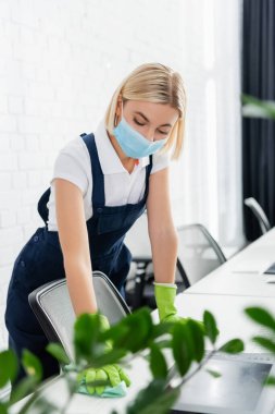 Bulanık ön plandaki fabrikanın yakınındaki tıbbi maske temizleme masasında temizlikçi 