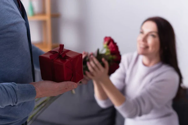 Man Holding Gift Box Buurt Van Vrouw Met Bloemen Wazig — Stockfoto