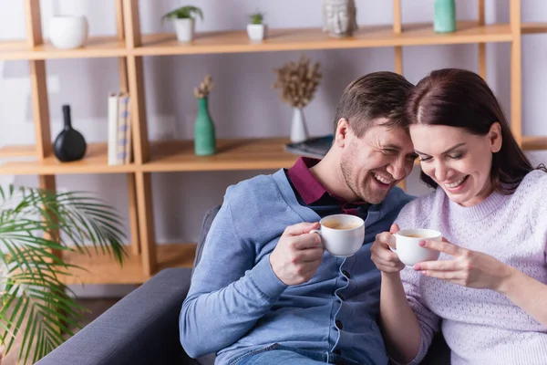 Smiling Woman Holding Cup Husband Couch — Stock Photo, Image