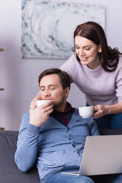 Mujer Sonriente Dando Taza Marido Con Ordenador Portátil Primer Plano — Foto de Stock