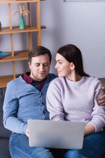 Mann Umarmt Ehefrau Und Benutzt Laptop Auf Verschwommenem Vordergrund — Stockfoto