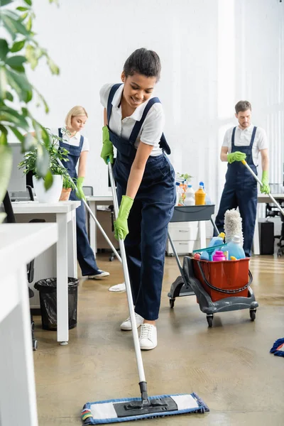 Positive African American Cleaner Washing Floor Plant Blurred Foreground Office — Stock Photo, Image