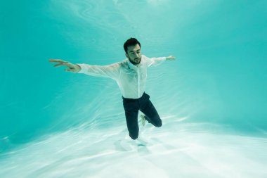 Yüzme havuzunda dalan gömlekli Müslüman iş adamı 