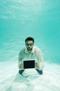 Gözlüklü Arap yönetici su altında dijital tablet tutuyor 