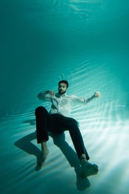 Resmi olarak Müslüman bir adam suyun altında kapalı gözlerle yüzer. 
