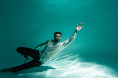 Bearded arabian businessman swimming in pool with turquoise water  clipart