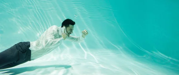 Smiling Arbian Businessman Showing Yes Gesture While Talking Smartphone Underwater — Stock Photo, Image