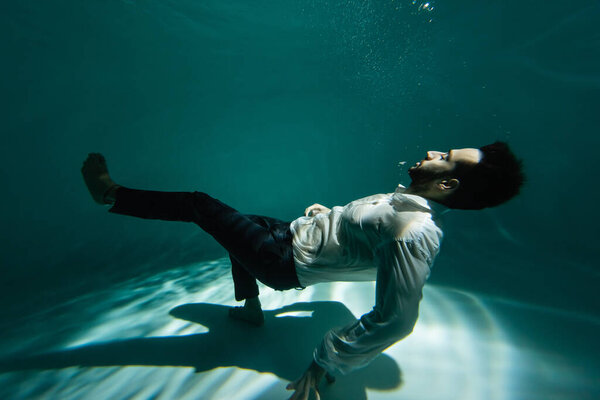 Арабский бизнесмен плавает на дне бассейна со светом 