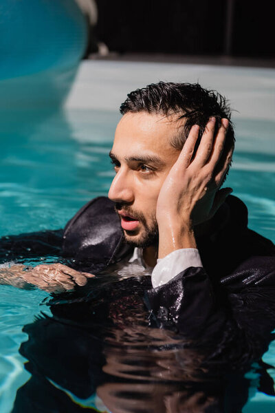 Arabian businessman in wet suit looking away in pool 