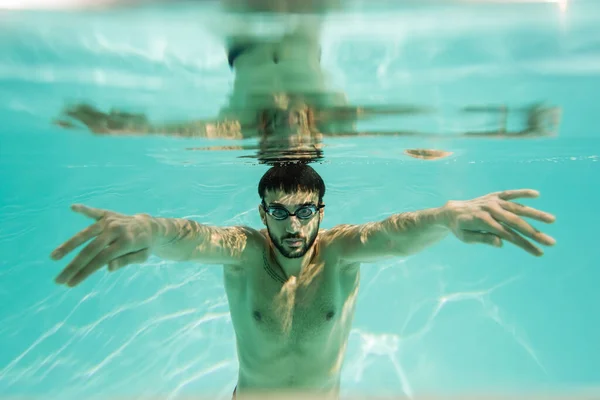 Arabian swimmer diving underwater with reflection