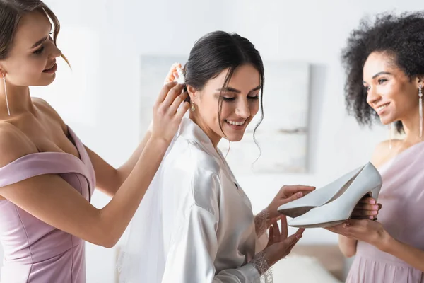 Mujer Afroamericana Sosteniendo Zapatos Blancos Cerca Novia Durante Los Preparativos —  Fotos de Stock