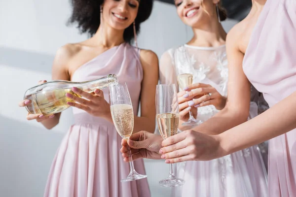非洲裔美国女人把香槟酒倒入新娘和伴娘的酒杯中 模糊了背景的剪影 — 图库照片