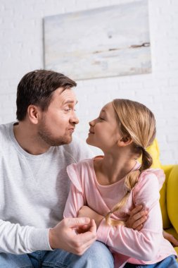 Oyuncu baba ve kızı evde eğlenirken birbirlerine somurtuyorlar.