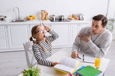 Heyecanlı çocuk ödevlerini yaparken babasının yanında fikir jesti yapıyor.