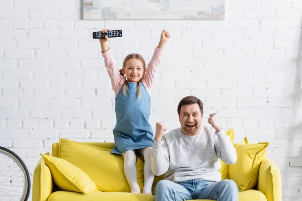 快乐的爸爸和孩子在家里看电视时表现出成功的姿态 — 图库照片