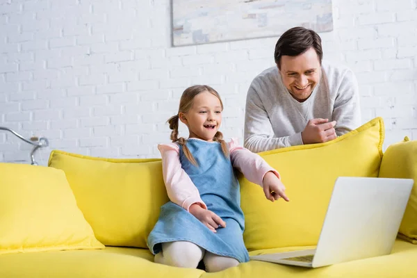 Aufgeregtes Kind Zeigt Auf Laptop Während Film Neben Lächelndem Vater — Stockfoto