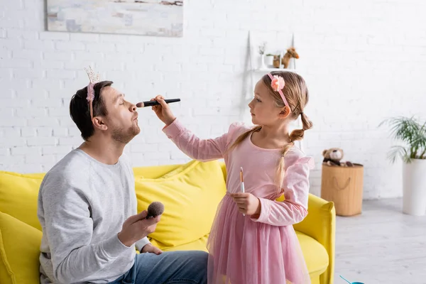 Homem Brinquedo Coroa Sentado Sofá Enquanto Filha Aplicando Maquiagem — Fotografia de Stock