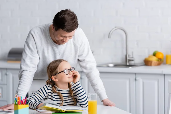 Homme Debout Près Fille Souriante Faisant Des Devoirs Dans Cuisine — Photo