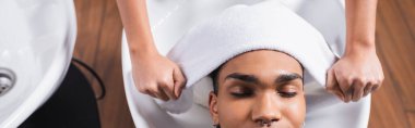 Afro-Amerikan adam pankartın yanında havluyu tutan kuaför. 