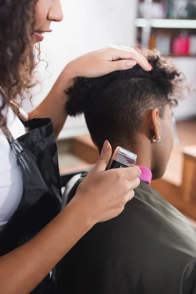 Africano Americano Cabeleireiro Segurando Trimmer Perto Cliente Fundo Borrado — Fotografia de Stock