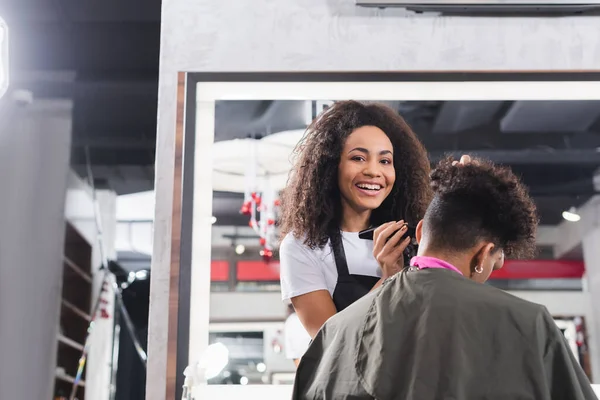 African American Hairdresser Smiling Camera While Holding Trimmer Man Salon — Stock Photo, Image