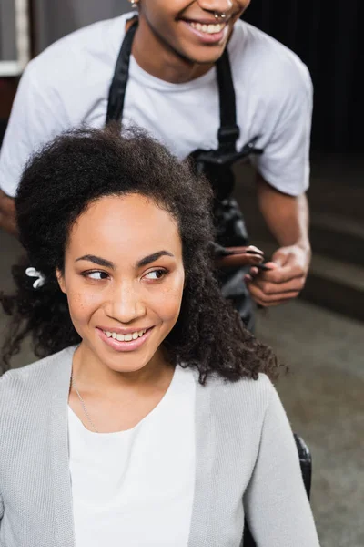 Smilende Afrikansk Amerikansk Kvinde Ser Væk Nær Frisør Med Hår - Stock-foto