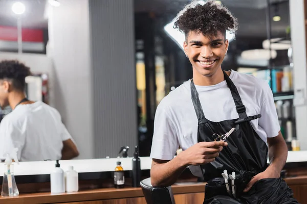 Jovem Cabeleireiro Afro Americano Segurando Tesoura Pente Perto Cadeira — Fotografia de Stock