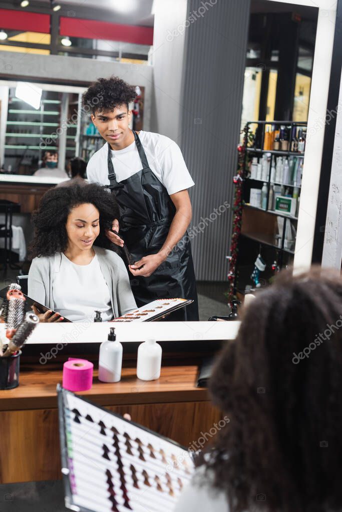 African american woman holding hair color swatches near hairstylist 