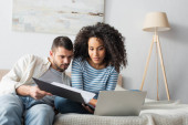 interracial couple looking at laptop in bedroom