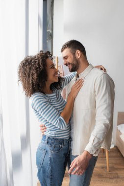 Mutlu ırklar arası çift yatak odasında sarılıyor.