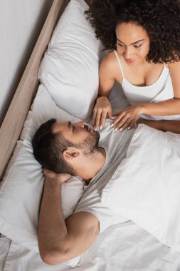Yatak odasında birbirine bakan çok ırklı bir çiftin yüksek açılı görüntüsü