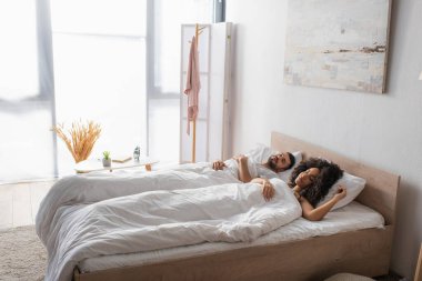 Çok ırklı bir çift yatakta yatıyor.