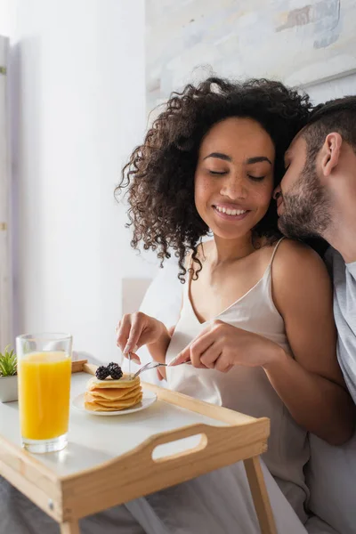 Bearded Man Kissing Happy African American Woman Holding Cutlery Pancakes — Stock Photo, Image