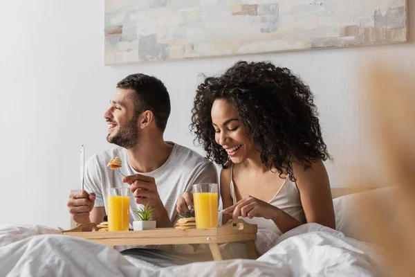 Cheerful Multiethnic Couple Eating Breakfast Bed — Stock Photo, Image