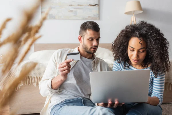 Interracial Couple Shopping Online While Using Laptop Bedroom Blurred Foreground — Stock Photo, Image